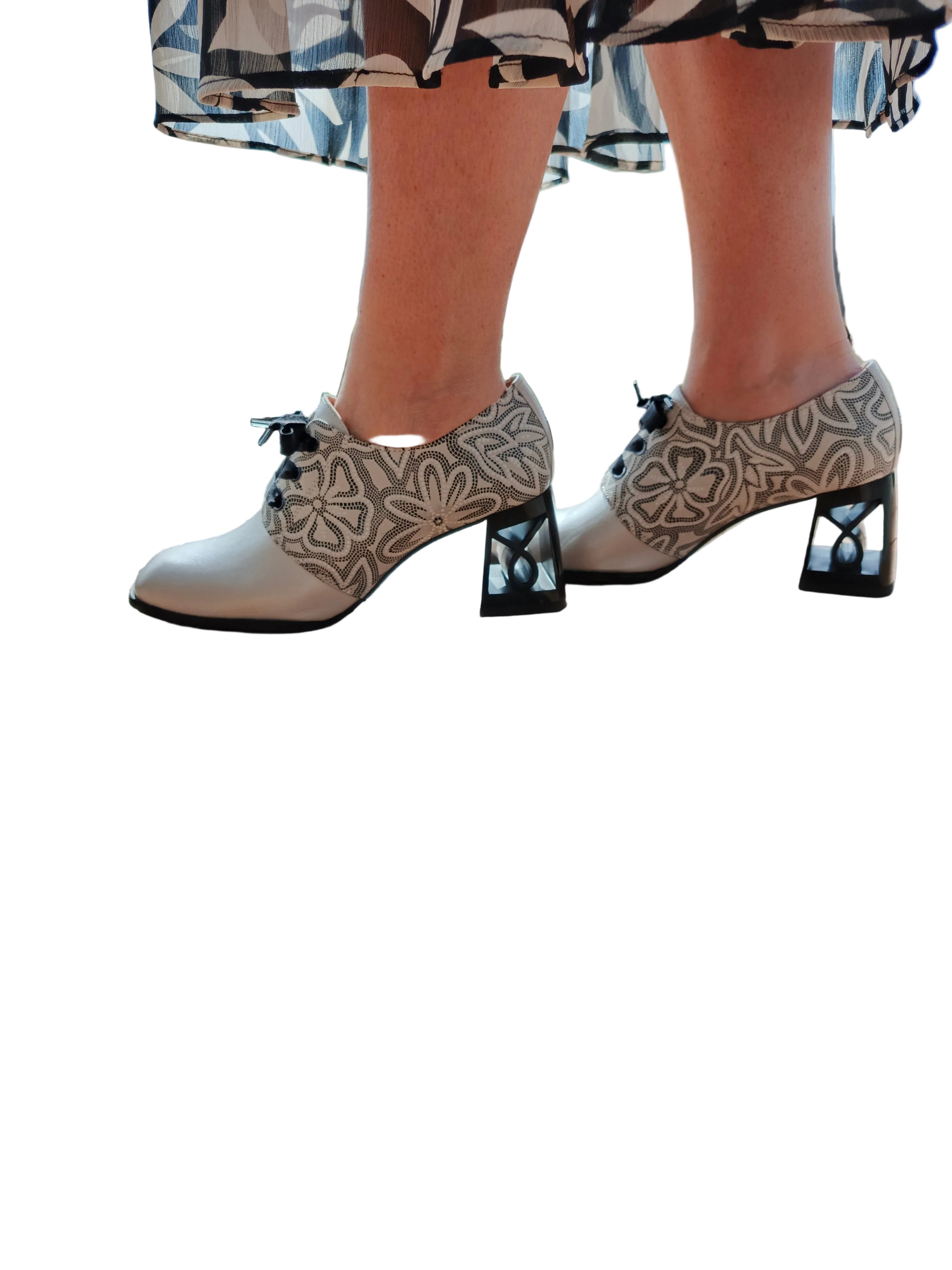Women's handmade leather shoes with floral pattern and geometric block heels on wooden floor