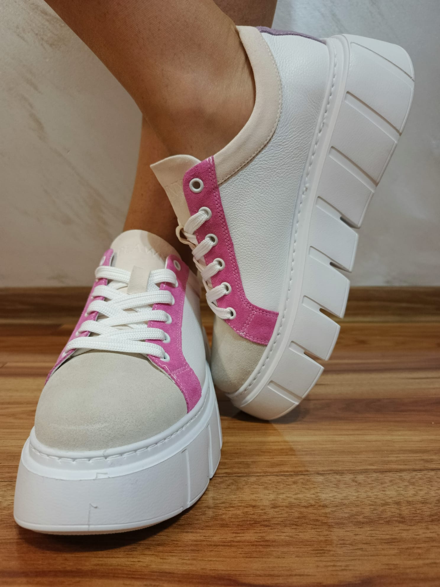 White and pink leather platform sneakers with chunky sole on wooden floor
